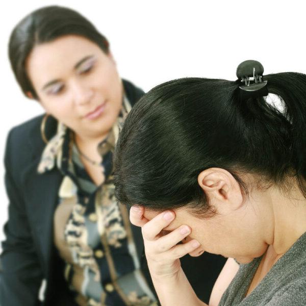 A visibly upset woman talking with a counselor